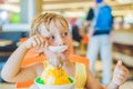 Lovely blond little boy eating ice-cream in city cafe in summer Royalty Free Stock Photo