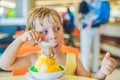 Lovely blond little boy eating ice-cream in city cafe in summer Royalty Free Stock Photo