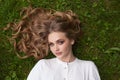 Lovely blonde woman with long healthy hair lying on green grass outdoors Royalty Free Stock Photo