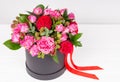 Lovely bouquet of pink and red roses and red ribbon in a circular black box on white wooden table Royalty Free Stock Photo