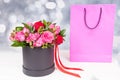 Lovely bouquet of pink and red roses and red ribbon in a circular black box near pink gift bag Royalty Free Stock Photo