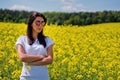 Lovely brunette in sunglasses stay in rapeseed field. Royalty Free Stock Photo