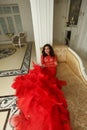 Lovely brunette woman in red dress relaxing in luxurious interior