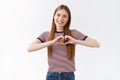 Lovely, caring young girlfriend with long fair hair show heart sign, smiling tenderly and gaze camera, sincerely confess Royalty Free Stock Photo