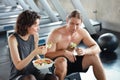 Lovely caucasian couple fitness man and woman take a rest and eating salad in gym after finish fitness training with happy smiling Royalty Free Stock Photo