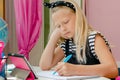 Lovely caucasian left handed school girl bored while doing her homework. Education concept