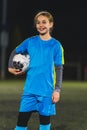 lovely Caucasian little footballer girl in a blue uniform posing with a soccer ball, medium shot Royalty Free Stock Photo