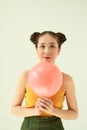 Lovely cheerful Asian teenager girl holding pink air balloon with two buns hairstyle over light background