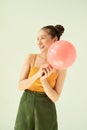 Lovely cheerful Asian teenager girl holding pink air balloon with two buns hairstyle over light background