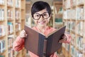 Lovely child with glasses holding book in library Royalty Free Stock Photo
