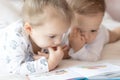 Lovely children - brother and sister, reading a book, on the bed. Close up of children in bed reading a book. A boy and Royalty Free Stock Photo