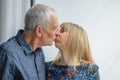 Lovely Couple with Age Difference Kissing near Opened Window inside the House During Spring Time.