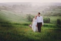 Lovely couple, bride and groom posing in field during sunset, lifestyle Royalty Free Stock Photo