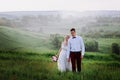 Lovely couple, bride and groom posing in field during sunset, lifestyle Royalty Free Stock Photo