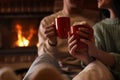 Lovely couple with delicious cocoa near burning fireplace at home. Winter vacation