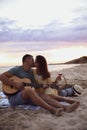 Lovely couple with guitar and basket on beach at sunset Royalty Free Stock Photo