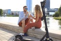 Lovely couple having fun driving electric scooter through the city, having a break, drinking coffee Royalty Free Stock Photo