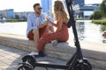 Lovely couple having fun driving electric scooter through the city, having a break, drinking coffee Royalty Free Stock Photo