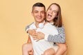 Lovely couple having fun while man piggybacking his girlfriend isolated over beige background expressing positive emotions, wife Royalty Free Stock Photo