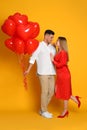 Lovely couple with heart shaped balloons on yellow  background. Valentine`s day celebration Royalty Free Stock Photo