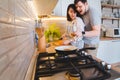 Lovely couple hugging on the kitchen while cooking breakfast