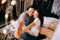 Lovely couple hugging on their bed decorated with garland lights at home indoors in the bedroom Royalty Free Stock Photo