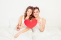 Lovely couple in love holding red paper heart in bed Royalty Free Stock Photo