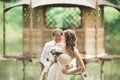 Lovely couple in love kissing each other on the day wedding, standing in the park outdoors near lake