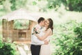 Lovely couple in love kissing each other on the day wedding, standing in the park outdoors near lake