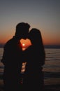 Lovely couple of lovers posing and kissing of the sunset on the sea coast