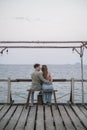 Lovely couple sitting on the wooden bench on the pier Royalty Free Stock Photo