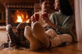 Lovely couple with sweet cocoa near fireplace, focus on legs