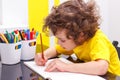 Lovely curly-headed boy in yellow t-shirt writes copy-books, letters Royalty Free Stock Photo