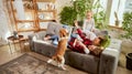 Lovely cute family, parents and child relaxing at home, playing with beagle dog in their living room on sunny day Royalty Free Stock Photo