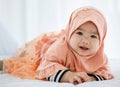 A lovely cute innocent Muslim infant in hijab dress creeping and crawling on bed and looking to camera Royalty Free Stock Photo