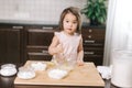 Lovely cute little girl wearing white dress is whisking eggs in mixing bowl with fork Royalty Free Stock Photo