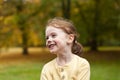Lovely cute red-haired little girl in the autumn park outdoors. Lovely baby in front of falling leaves Royalty Free Stock Photo