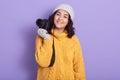 Lovely dark haired woman taking photo with camera isolated over lilac background, adorable female dresses yellow knitted sweater,