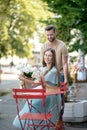 Bearded male helping young female with bouquet of white flowers to sit down at the table