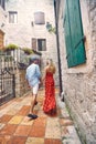 Lovely date. Couple on walk. Woman in red sultry summer dress and stylish handsome man holding hands. Old buildings. Date,