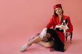 Lovely fair-skinned young woman sitting on floor with Boston Terrier dog on pink background. Royalty Free Stock Photo