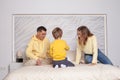 Lovely family, cute parents, mom and dad with adorable child son sitting on the bed Royalty Free Stock Photo