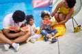 Lovely family of four sitting by the pool eating watermelon slices together. Mother and father with their two kids Royalty Free Stock Photo