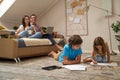 Happy mother and father sitting on sofa and watching movie on laptop while their kids, little boy and girl lying on the Royalty Free Stock Photo