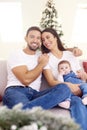 Lovely family with their baby girl relaxing on sofa at home during Christmas Royalty Free Stock Photo