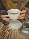 Lovely female hands holding a white Cup of hot coffee. A girl in a Cozy warm knitted sweater holding a Cup of hot coffee
