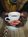 Lovely female hands holding a white Cup of hot coffee. A girl in a Cozy warm knitted sweater holding a Cup of hot coffee Royalty Free Stock Photo