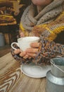 Lovely female hands holding a white Cup of hot coffee. A girl in a Cozy warm knitted sweater holding a Cup of hot coffee Royalty Free Stock Photo