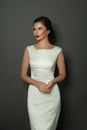 Lovely female model woman wearing white trendy silk dress posing on black background