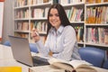 Lovely female student working on laptop at the library